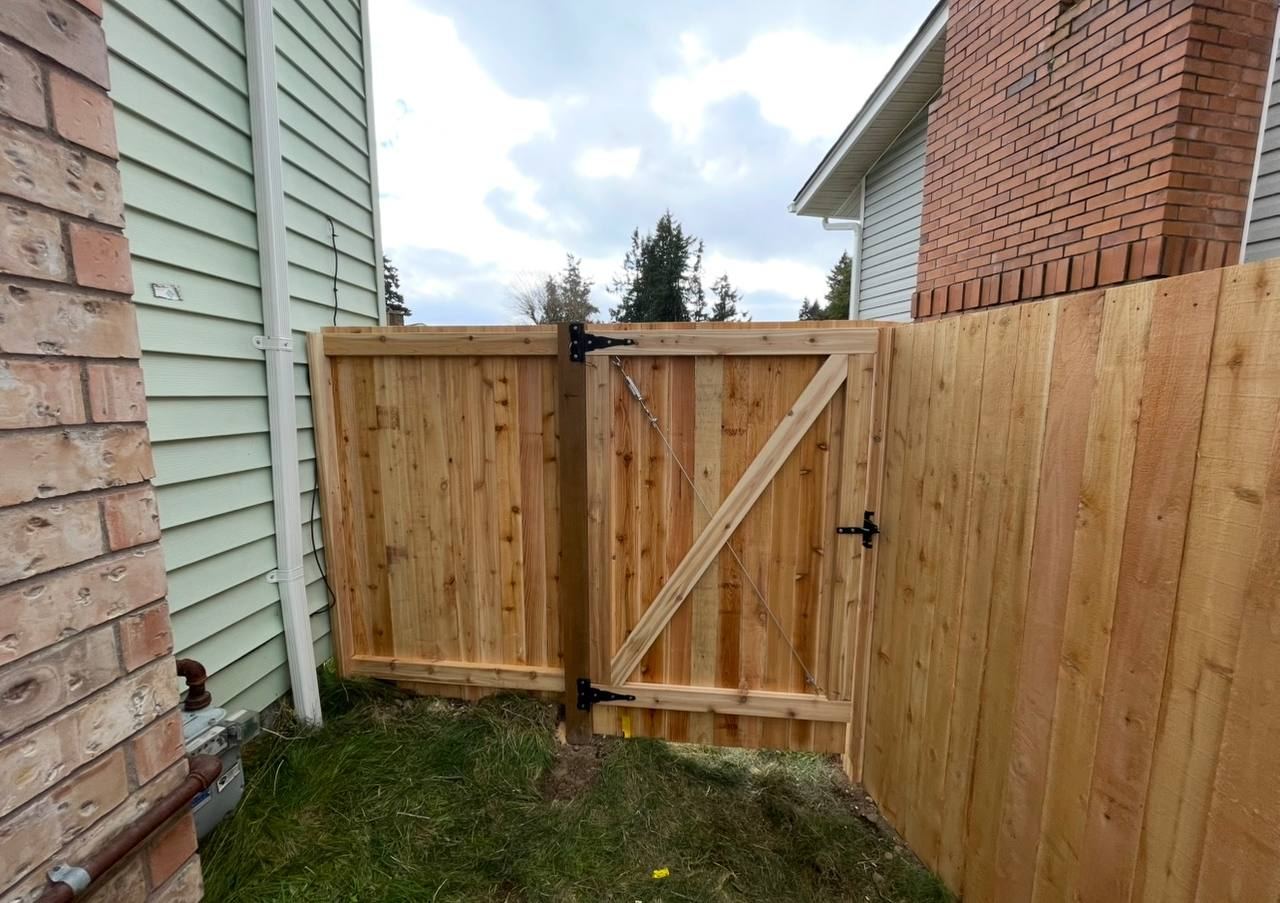 Cedar privacy fence and braced gate beside brick chimney